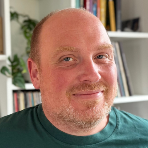 Freek Van der Herten, smiling, in front of a bookshelf at home.